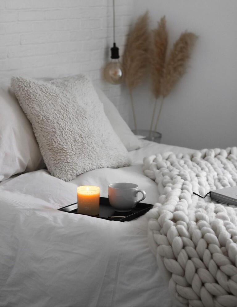 A candle and blanket on a bed, Scandinavian style