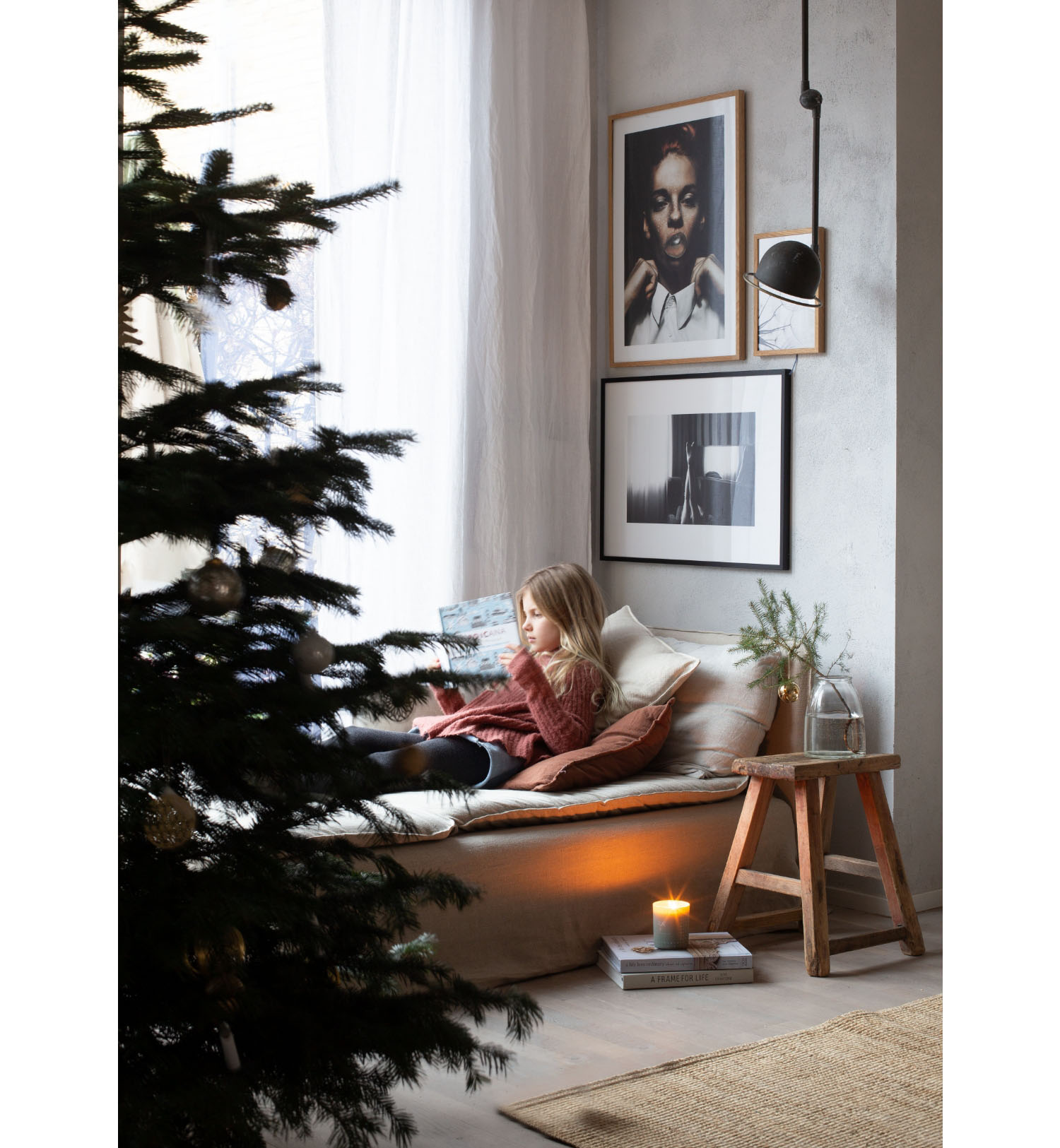 girl reading a book next to christmas tree